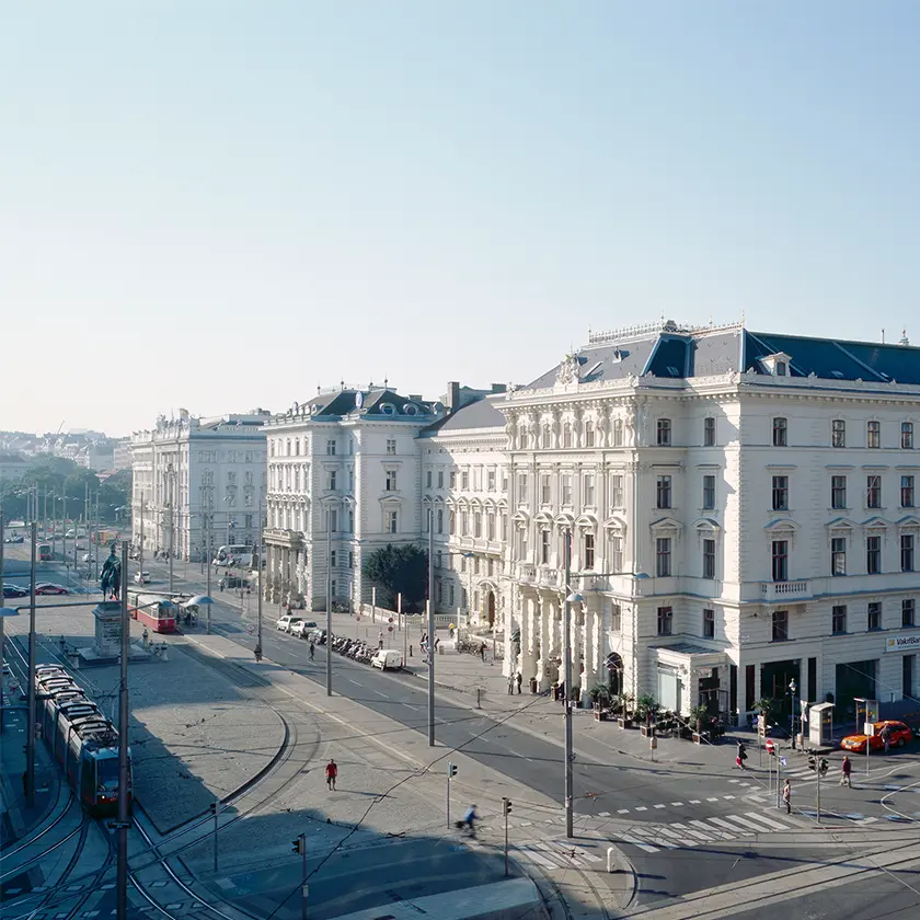A vintage typewriter placed on a red couch. Next to the typewriter, there is a brown leather handbag on a white table. There is also a piece of paper with some printed text and drawings.